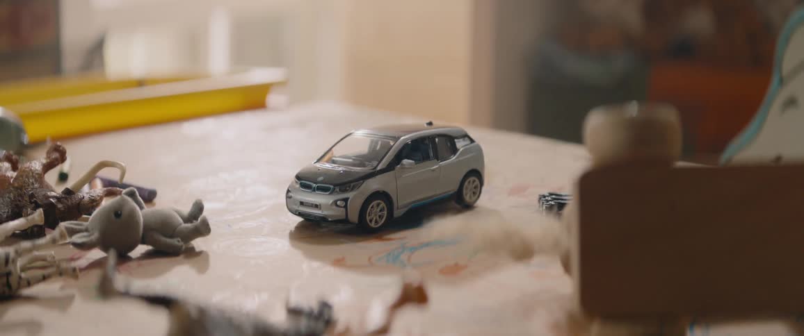 A toy car resting on a desk indoors during the day