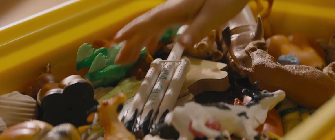 A child reaches into a plastic bin filled with toys and takes a rocket