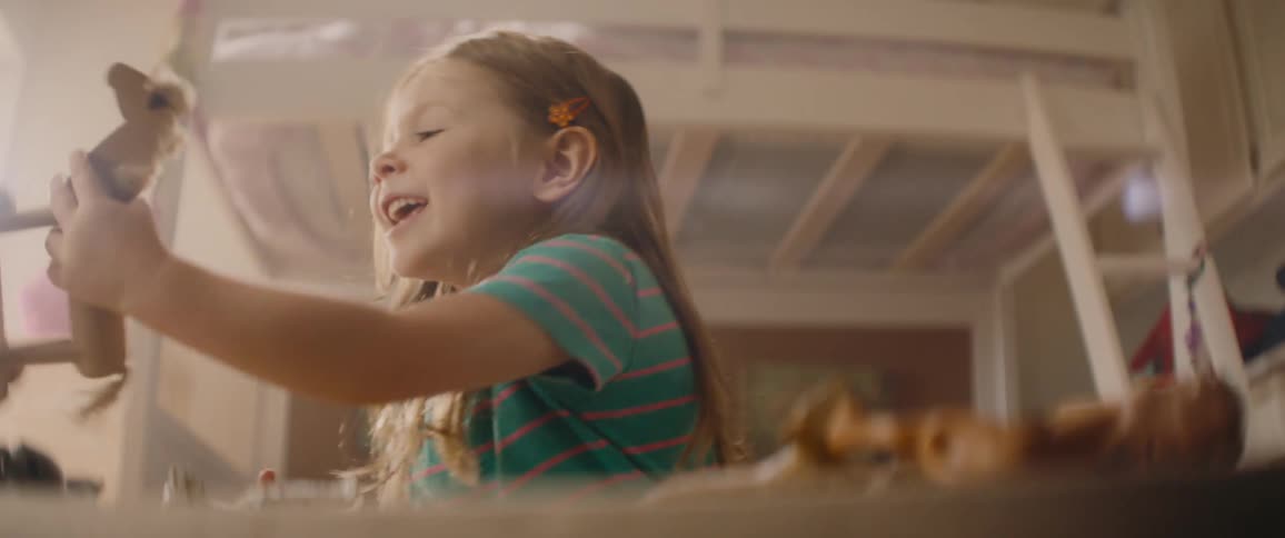 Little girl with brown hair and blue t-shirt plays with toy horse in front of bunk bed in bedroom