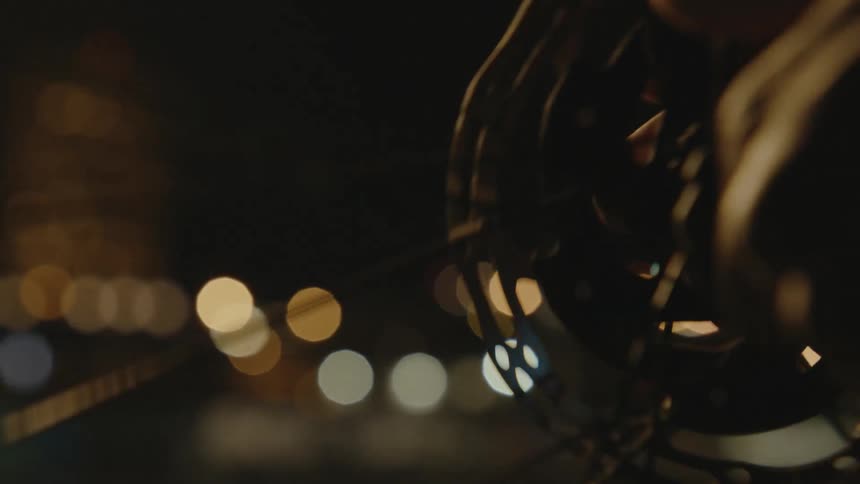 A person spins the wheel of a bicycle using their hand while outside at night
