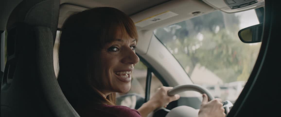 A woman is driving a car down a street in spring