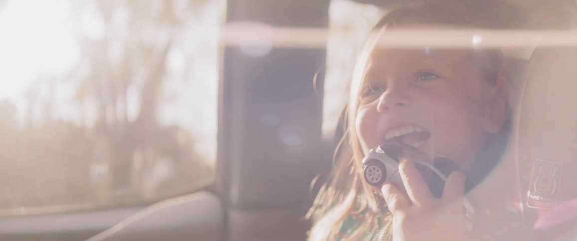 A child riding in a car with a car toy