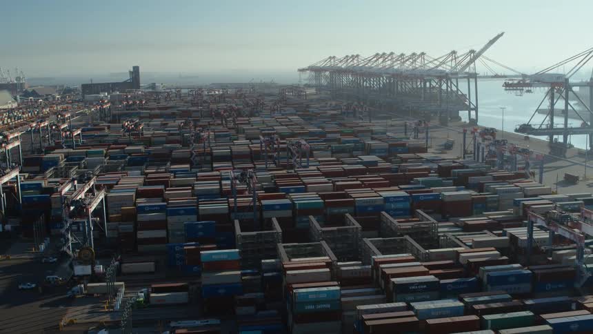 A shipping dock with many containers and cranes near the water