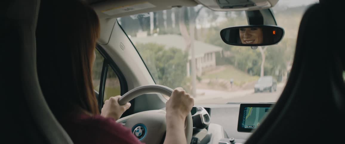 A woman is driving an automobile on a neighborhood street