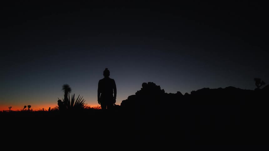 The silhouette of a person walking through the badlands at sunset