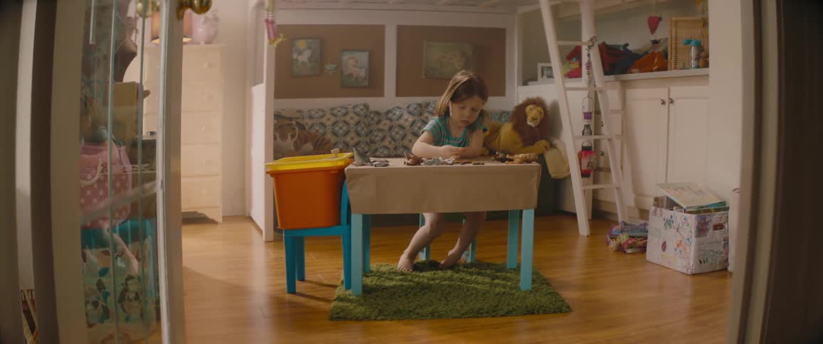 A little girl is sitting at her desk coloring with crayons