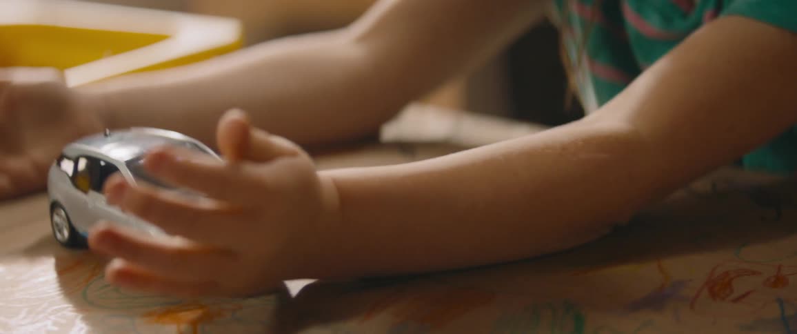 A little girl is playing with a toy car on her desk