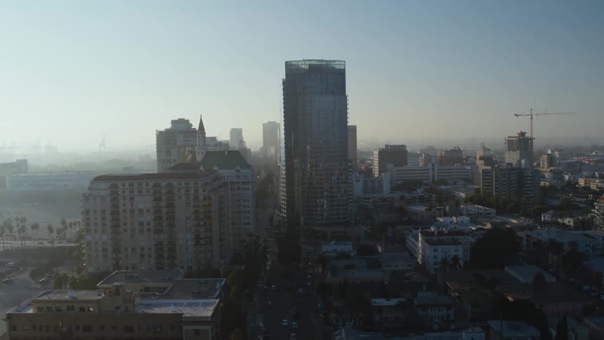 Aerial view of city skyscrapers and buildings with vehicles driving on highway at dawn