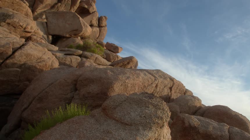 The sun shines on boulders and rocks along a mountainside