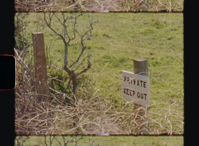 A fence with a keep out sign on a grassy field Big Sur California Super8 4k Film Scan