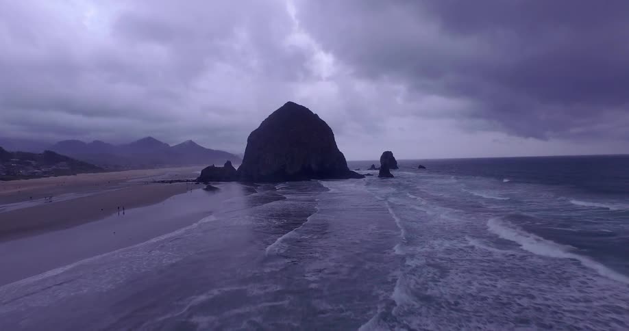 Aerial view of a large rock on a beach on a very cloudy day
