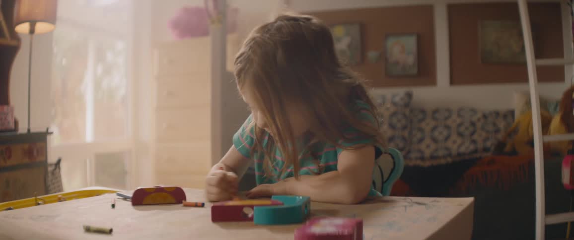 Girl sits at table at home coloring with crayons