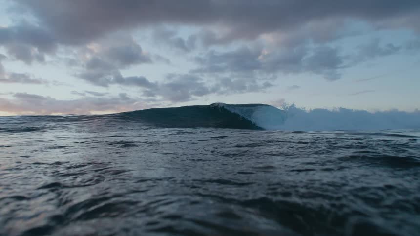 Ocean wave breaks against the shore at dusk