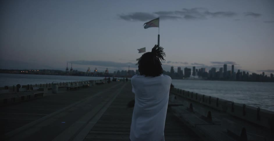 A man is walking on the boardwalk with the city in the distance