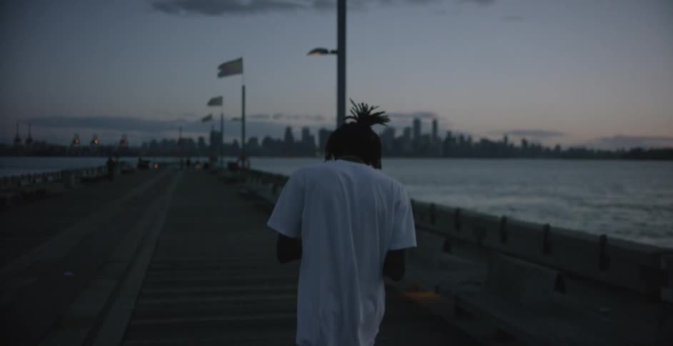 A man is walking along a pier at sunset