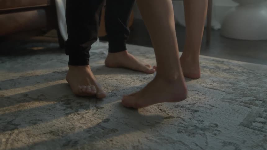 Couple slow dances barefoot on living room rug