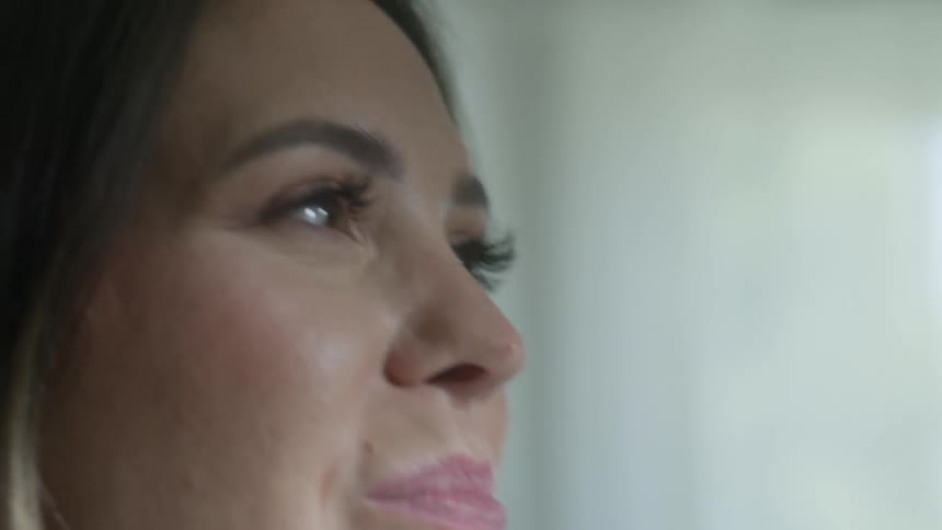 Woman smiles as she talks and then puts food in her mouth and chews it