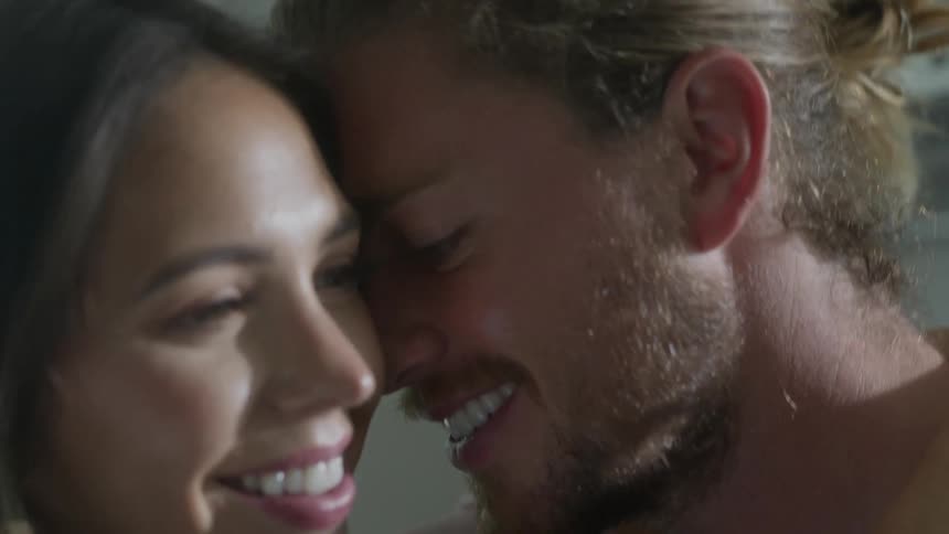 Couple smiles and talks as they stand face to face cuddling