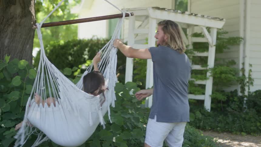 A man pushes a woman on a hammock