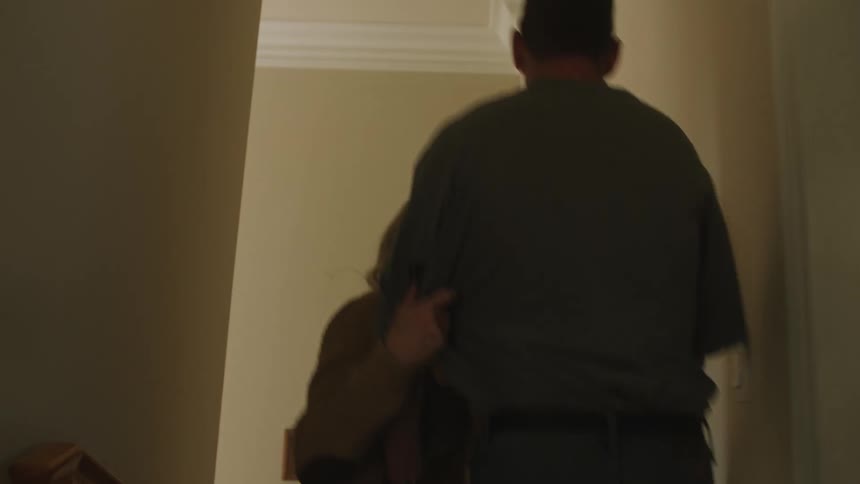 A man pushes his wife down the stairs after she follows him down a hallway