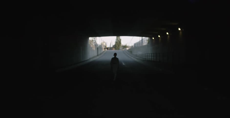 A person is walking in a dark tunnel