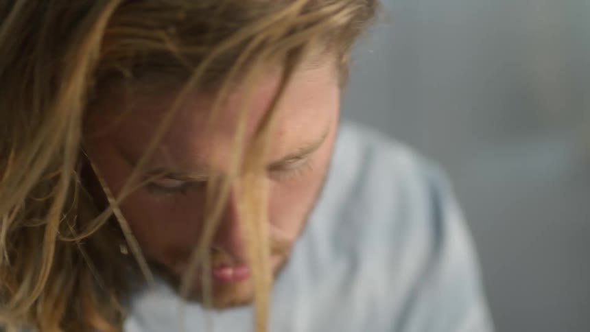 Blonde man looks downward as he scans back and forth
