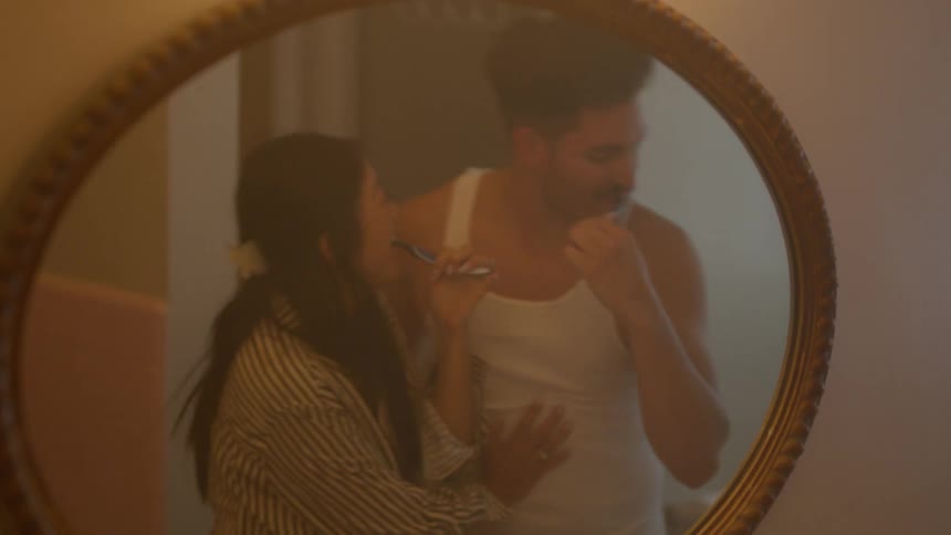 A man and woman are brushing their teeth together