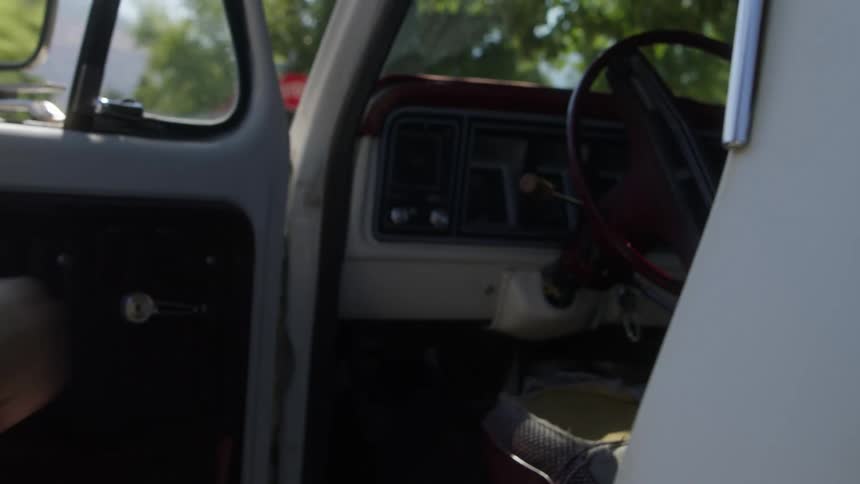 A man runs to the drivers side of a white truck and opens the door and jumps in