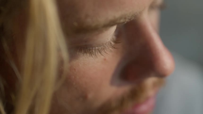 Blonde man with mustache waits with eyes closed