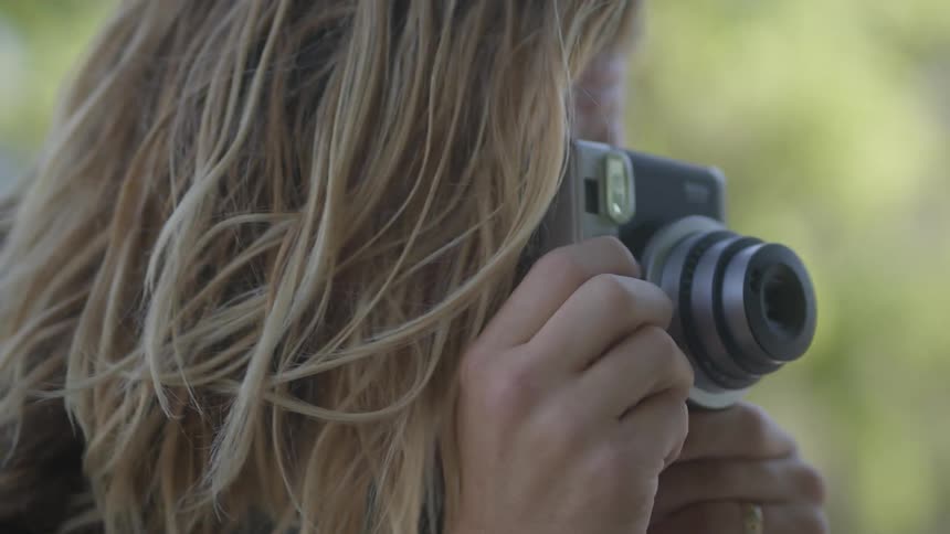 A man with long blond hair is talking to someone as he takes a picture