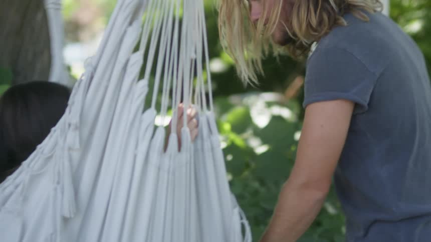 A man pushes a woman on a hammock