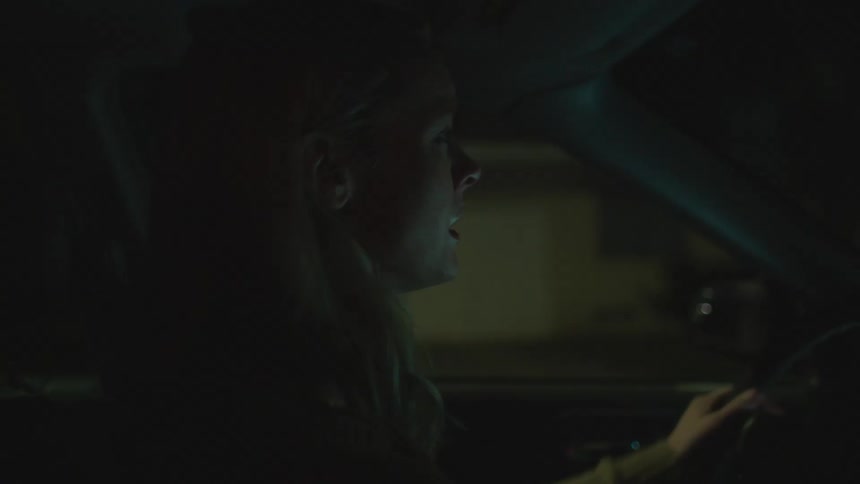 Blonde woman drives car through neighborhood at night anxiously searching the area