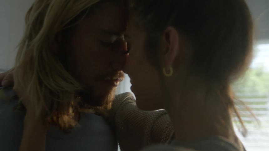 A man and woman slow dancing at home near a window