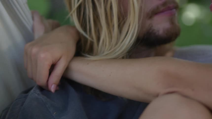 Couple sit in hammock cuddling and talking together