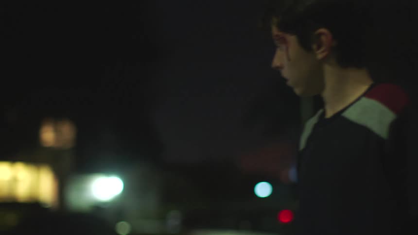 A teen walks down a city street bleeding from the forehead and runs into his mother who hugs him