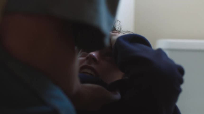 A boy holds his hand to his head defensively as he is threatened and hit by a man
