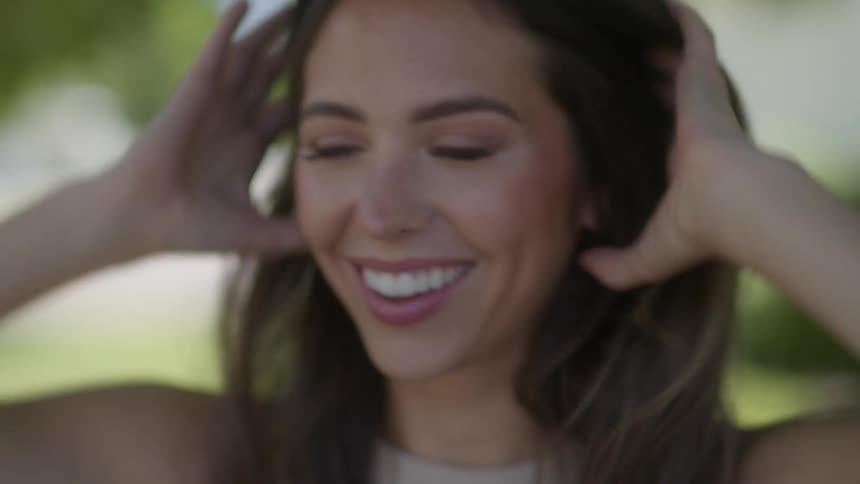 Woman smiles and combs back her hair as she gestures and talks