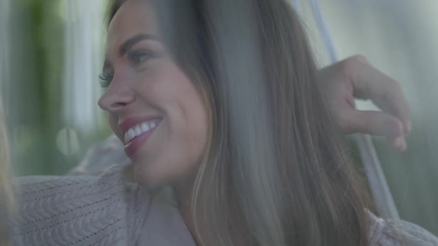 Husband and wife smile as they sit close together on a porch swing