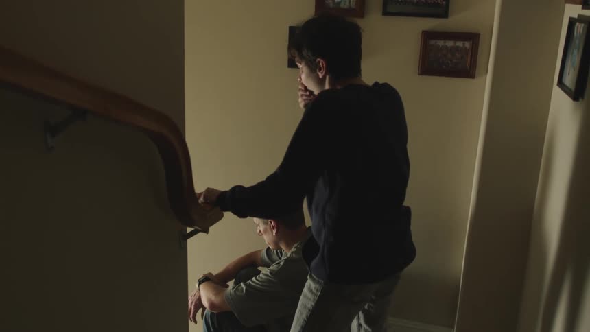 A boy runs past his father sitting on the stairs