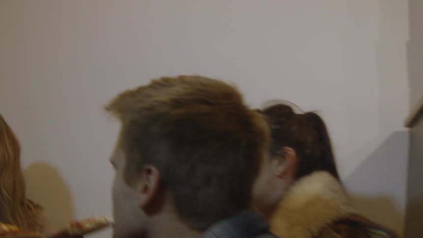 Young adults sitting in a booth eating pizza