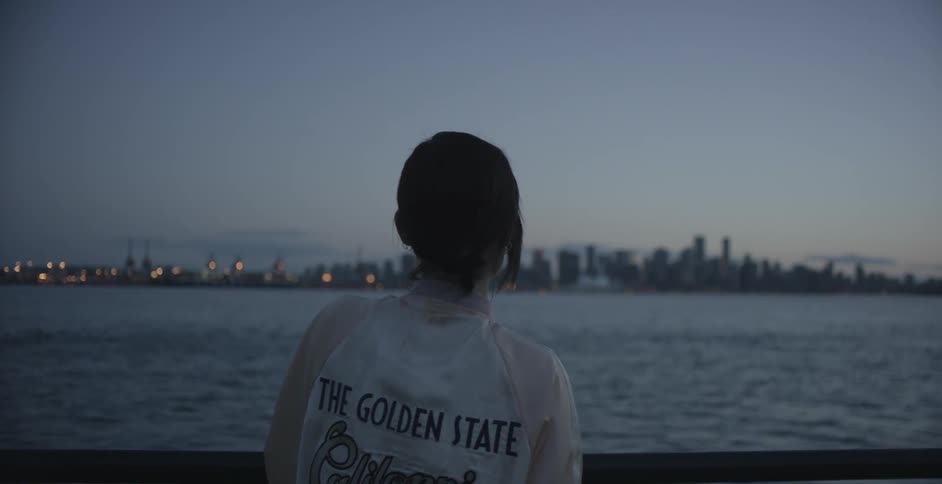 A woman looks at a city across the water