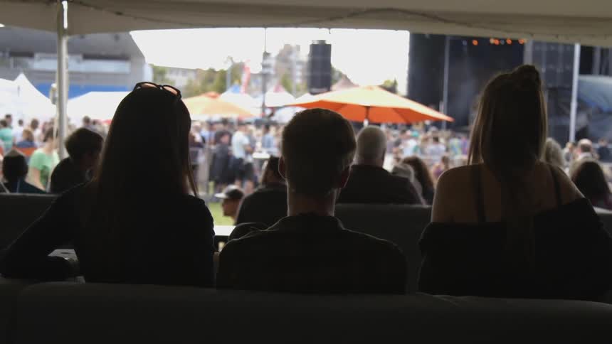 A group of friends sitting looking out at a large crowd of people.