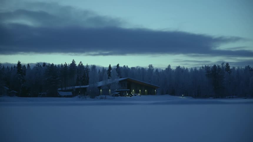 A rural cabin is surrounded by a blanket of snow
