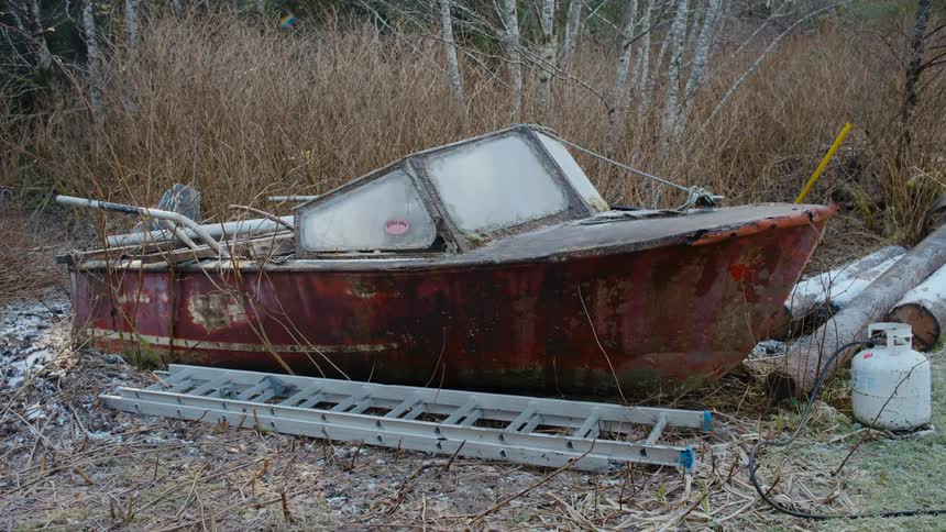 An old boat covered with frost is rusting in the woods