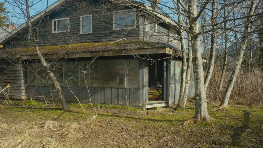 An abandoned house is shown in a rural area during fall