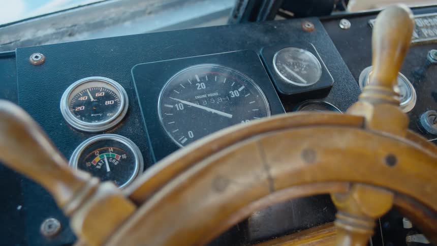 Wooden wheel sits near dashboard of ship helm