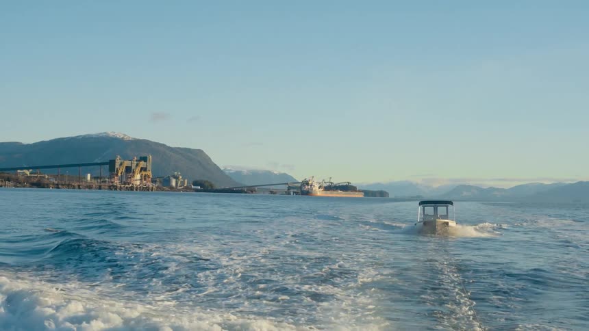 A boat moves through choppy waters past a marina