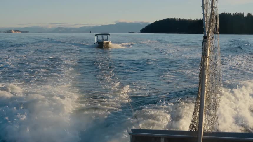 A boat is driving through the water at dusk