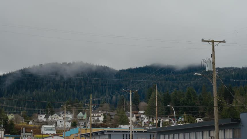 White houses sit in the small town next to the tree covered misty hills