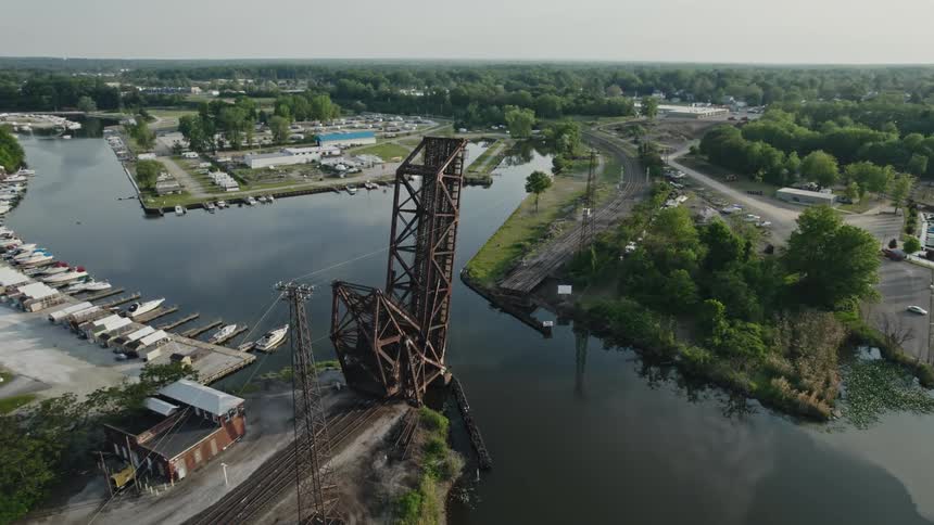 A drawbridge is lifted by a marina along a river